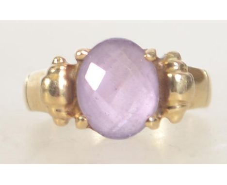 A hallmarked 9ct gold faceted amethyst ladies dress ring having scroll shoulders. Hallmark  London import 375. Total weight 5