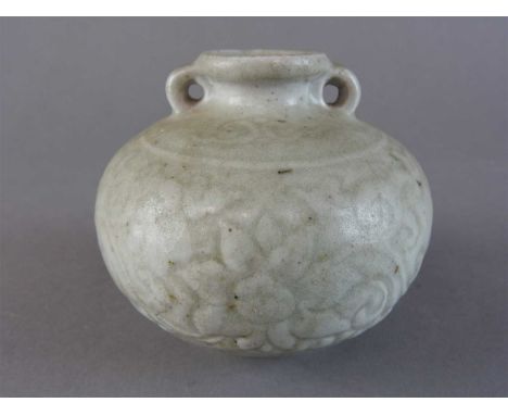 A Chinese celadon two handled squat globular jar, probably Ming Dynasty, carved with a bold scrolling lotus design above a st