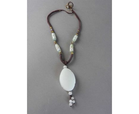 A Chinese white jade pendant of oval quatrelobed form carved to one side with a boy with hand fan attempting to swat a butter