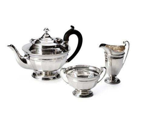 Comprising: a teapot, milk jug and sugar basin, the teapot with hinged cover, egg and dart rim, faceted body, ebonised leaf-c