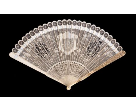 A CHINESE EXPORT IVORY BRISE FAN, EARLY 19TH C the guards carved to the centre with a monogram on a shield with mantling, mot