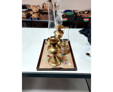 An oak twin handled serving tray together with two brass oil lamps and one further glass oil lamp 