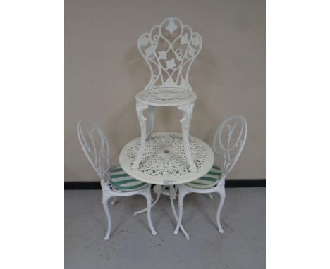 A cast metal circular garden table together with a pair of chairs and one further chair 