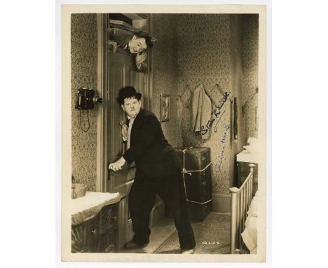 AUTOGRAPH. A signed black and white photograph of Stan Laurel and Oliver Hardy, 25.5cm x 20.5cm, showing the actors on set, p