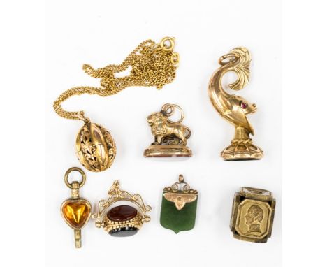 A collection of five pendant charms including a 9ct gold tri stone fob; together with a yellow metal cuboid incase bust seal 