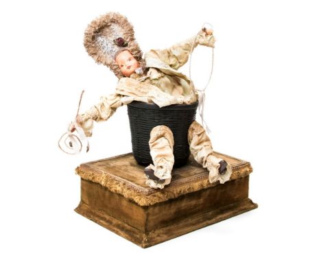 Automaton: A late 19th century music doll box, the doll having an automated movement, seated within a basket, composition fac