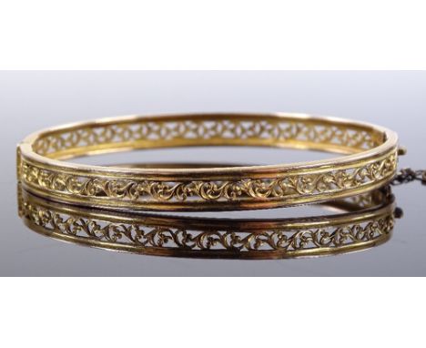 A 15ct gold hinged bangle, with pierced scroll work band, band width 6.2mm, internal diameter 59.3mm, 8.6g