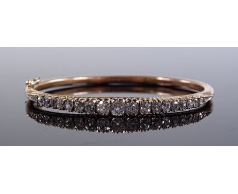 An unmarked gold graduated diamond set hinged bangle, central old-cut diamond approx 0.2ct, setting height 5mm, internal diam