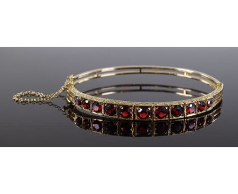 A Victorian 9ct gold graduated garnet hinged bangle, with open work back, internal diameter 60mm, 12.4g