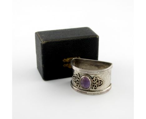 By Barrett and Thompsom, an Arts and Crafts silver napkin ring, Birmingham 1922, 'D' shape, applied with intertwined Celtic w