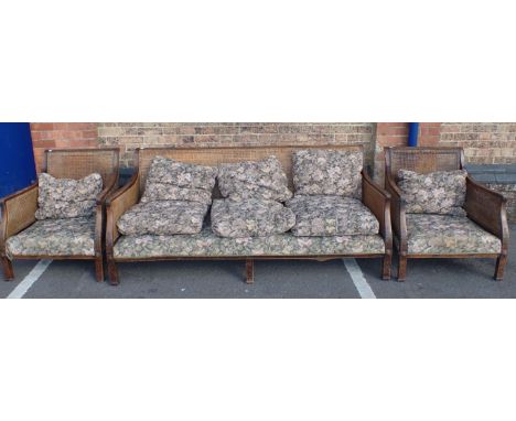 A 1920s CHIPPENDALE REVIVAL BERGERE SOFA AND ARMCHAIRS mahogany framed with gothic blind fret and acanthus carving, and doubl