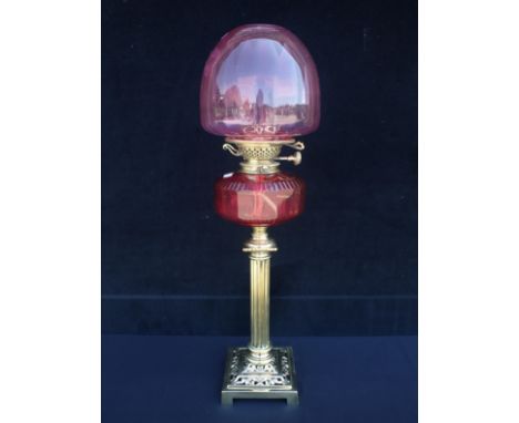 A VICTORIAN OIL LAMP WITH CRANBERRY SHADE and faceted cranberry reservoir, on polished brass column, with Young's Patent burn