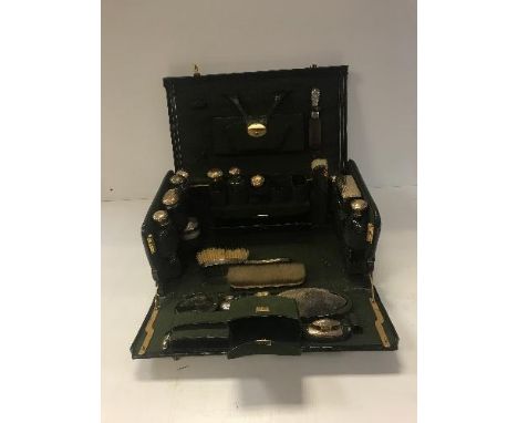 A circa 1900 green dyed leather and gilt lined travelling vanity case with collection of cut glass and beaten silver gilt mou