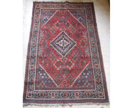 A Caucasian carpet, the central panel set with a lozenge shaped medallion on a red and blue ground with floral decoration, wi