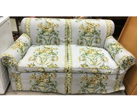 An early 20th Century upholstered two seat sofa on bun feet and castors with loose covers in Jean Munro "Versailles" linen fa