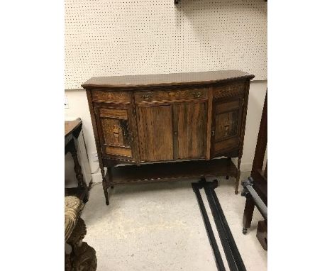 An Edwardian rosewood and inlaid side cabinet of canted form, the single central drawer above two cupboard doors flanked by t