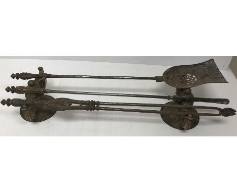 A set of three 19th Century Rococo style brass handled steel fire irons and a pair of gilt brass fire dogs of scrolling folia