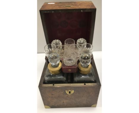 A George III burr oak veneered and brass bound tantalus containing four cut lead crystal decanters with gilt brass collars an
