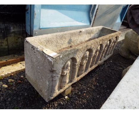 A reconstituted stone rectangular garden trough moulded with figures 