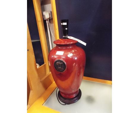 A red ground Jing Chang style ceramic table lamp raised on a hardwood base