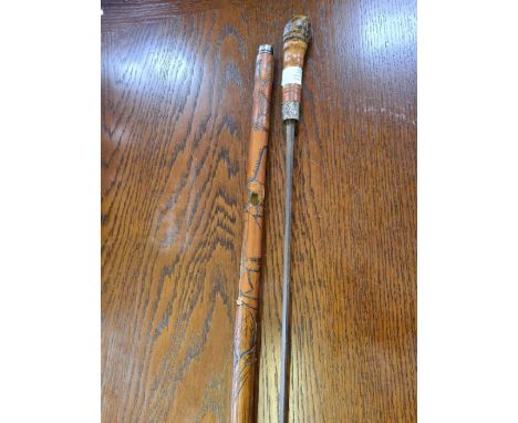 A carved bamboo sword stick with white metal tip and collar (damaged).