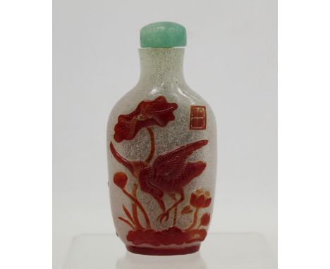 Chinese single red overlay snow ground snuff bottle carved with stork amongst lotus fronds and bird on fruit, seal mark and j