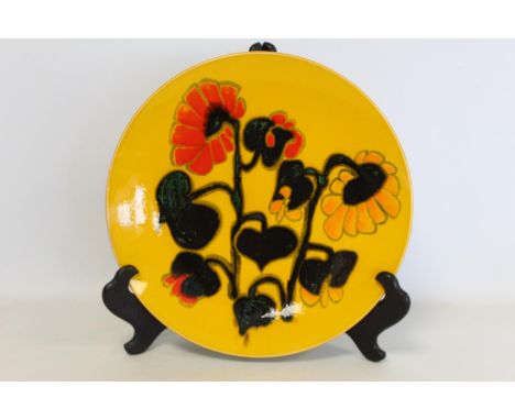 Large Poole Pottery Delphis circular charger, decorated with flowers on yellow ground. Painted initials J.S. 35.5cm diameter.