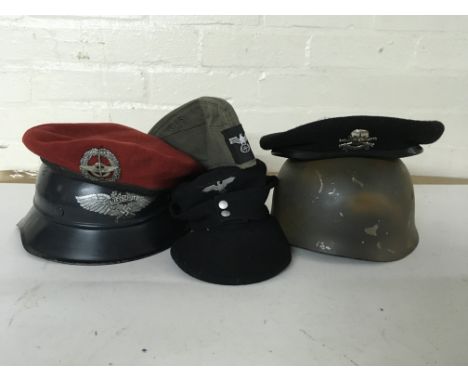 A group of headwear to include a pair of helmets to include an Airborne helmet and Luftschutz example, a pair of berets and t