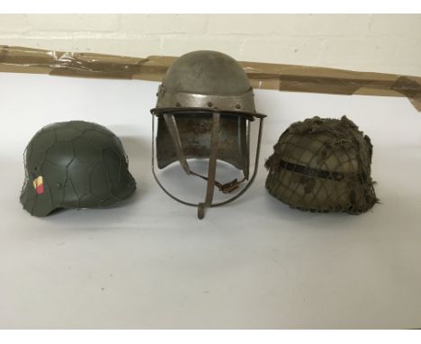 A group of three helmets including two German WW2 style helmets, one with netting and camouflage elements and an interesting 