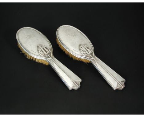 A pair of George V Art Deco silver mounted hair brushes by Omar Ramsden, London 1932, each oval head with openwork monogram '