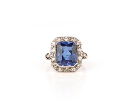 A synthetic sapphire and diamond ring, set with a scissor-cut synthetic blue sapphire within a border of single-cut diamonds,