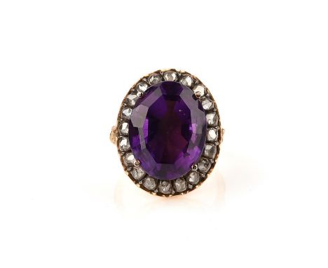 An amethyst and diamond cluster ring, the oval-shaped amethyst is set within a surround of rose-cut diamonds in silver collet