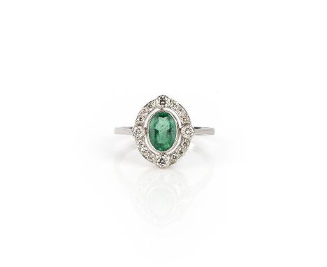 An emerald and diamond ring, collet-set with an oval emerald weighing 0.80 carats, within an open work border of brilliant-cu