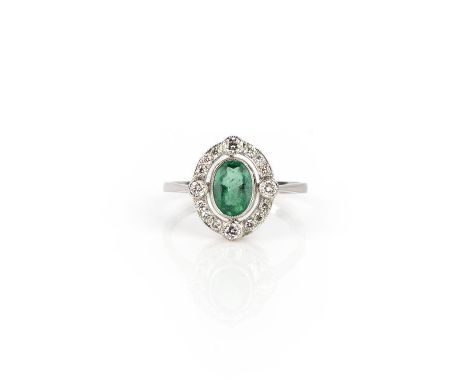 An emerald and diamond ring, collet-set with an oval emerald weighing 0.80 carats, within an open work border of brilliant-cu