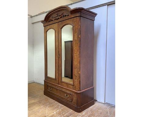 A Victorian figured walnut double wardrobe, the arched top over a frieze with applied scrolling acanthus and cartouche detail