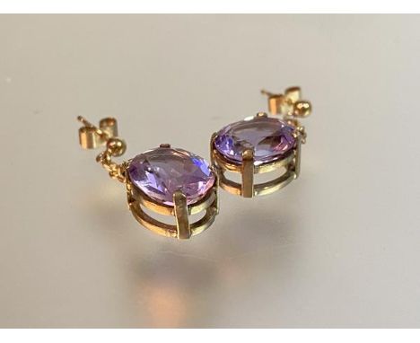 A pair of amethyst drop earrings, each with an oval-cut stone claw-set in yellow metal (believed to be 9ct gold), suspended f