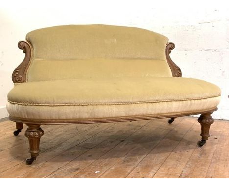 A late Victorian walnut-framed boudoir settee, the back with acanthus-carved "S" scroll terminals, upholstered in pale yellow