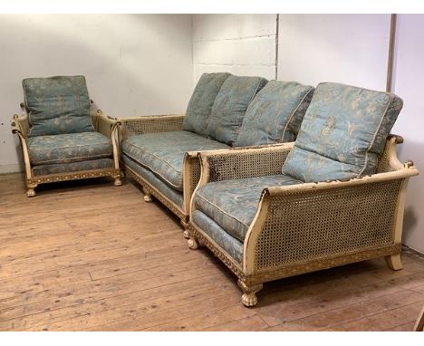 A cream and gilt-painted three piece bergere suite, 1920's, comprising a three-seat sofa, with acanthus and scrolled crest ra