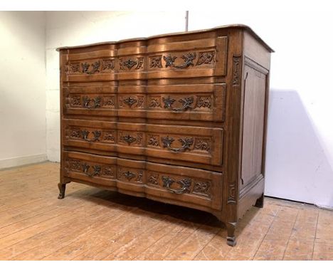 A Continental oak commode, late 19th century, of serpentine outline, the moulded top over four acanthus-carved drawers with f