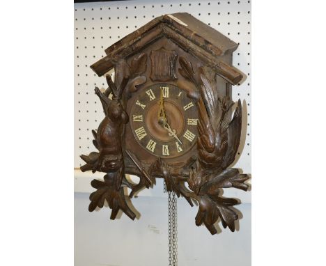 A German Black Forest cuckoo clock, 14cm dial with Roman numerals, the case carved  stags head and hanging game, 49cm high, c