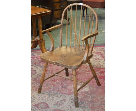 An early 19th century elm Windsor elbow chair, arched stick back, deep saddle seat, turned legs and stretcher, c.1820