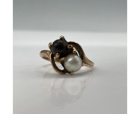 A vintage 14K gold bypass ring featuring a classic dual-pearl design with one white and one black pearl set in elegant prongs