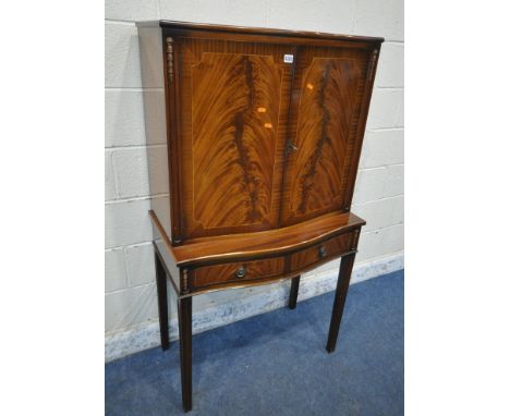 A MAHOGANY TWO DOOR DRINKS CABINET, the double doors enclosing a mirrored interior and cutting slide, over two drawers, on sq