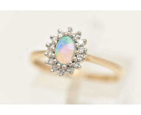 A 9CT GOLD OPAL AND DIAMOND CLUSTER, an oval opal, prong set with a surround of round brilliant cut diamonds, leading on to a