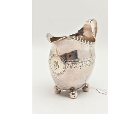 A GEORGE III SILVER MILK JUG, polished form with bright cut pattern and engraved monogram, raised on four ball feet, fitted w