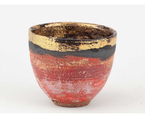 † ROBIN WELCH (1936-2019); a small stoneware vessel covered in red and pink glaze with black enamel and gold lustre rim, impr