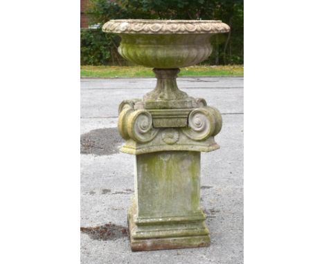 A reconstituted stone garden urn on stand, with egg and dart moulded border on a stylised Ionic column base, height 104cm, di