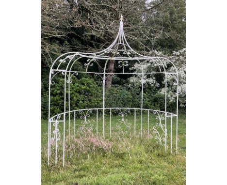 A white painted iron garden half arbour, D-shaped with C-scroll detailing, height approx 280cm, width approx 253cm.