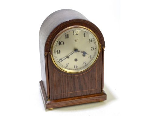 An Edwardian oak domed mantel clock, the circular dial set with Arabic numerals and manufacturer's initials 'FMS' beneath eag