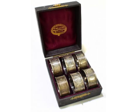 A cased set of six white metal napkin rings, each decorated with roundels of deities, the fitted case with gilt label for Chr